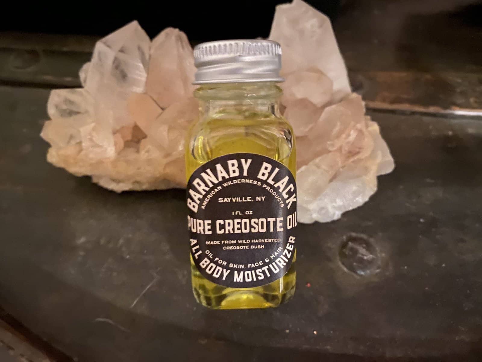 Barnaby Black pure creosote oil bottle displayed in front of raw healing crystals