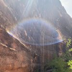 Natural red rock cliff with sun halo and energetic vortex effect captured near Sedona, symbolizing spiritual energy at Pyramid Wellness